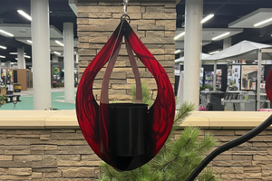 Red hanging planter with a plant against a stone wall background